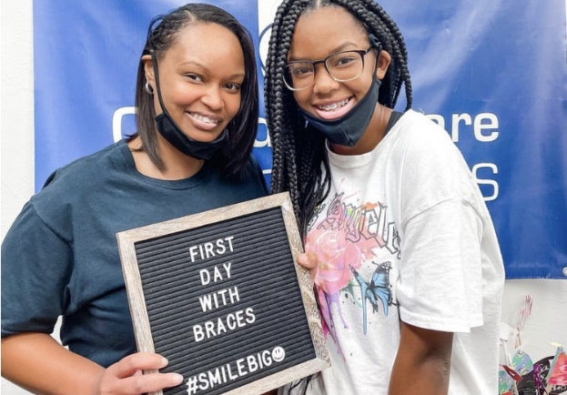 Oklahoma City orthodontic team member with young girl patient holding sign saying first day with braces