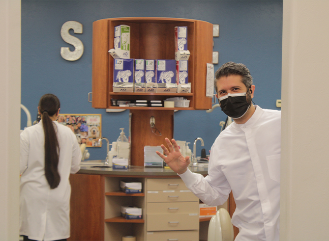 Doctor Ishani wearing face mask and waving hello to the camera in Oklahoma City orthodontic office