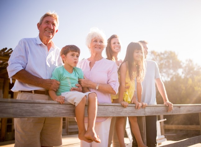 Three generations of smiling family standing on wooden bridge