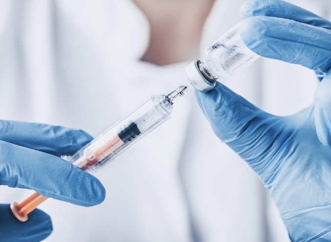 Medical professional drawing a syringe with clear liquid