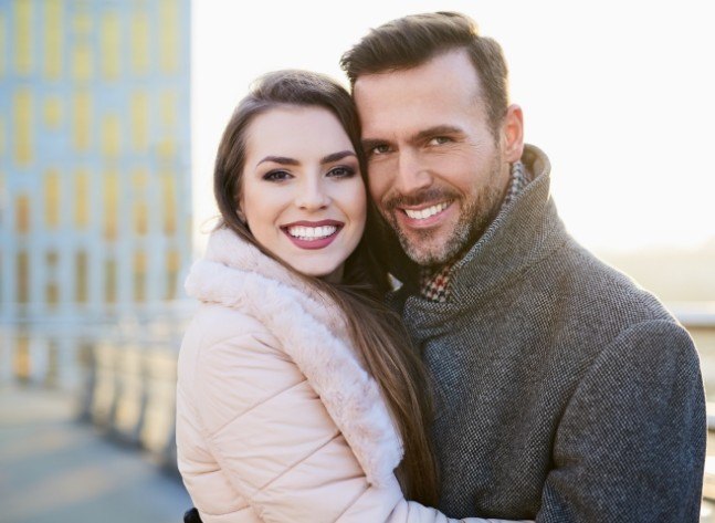 Man and woman in winter coats smiling outdoors after Botox in Oklahoma City