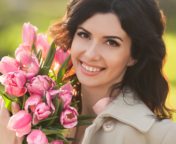 Woman with clear ceramic braces holding bouquet of flowers