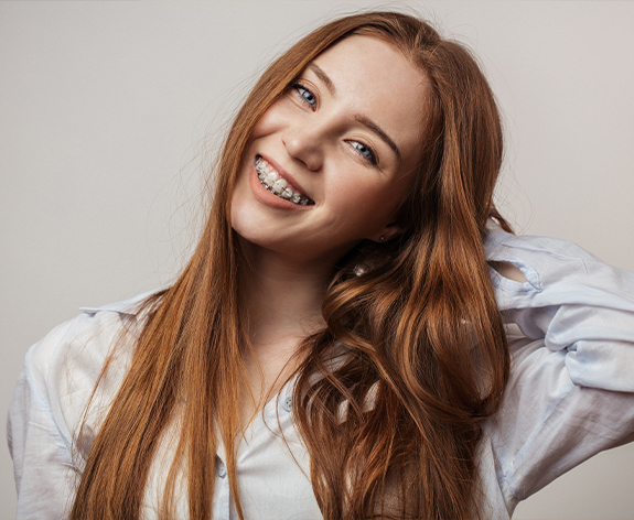 Young brunette woman with clear ceramic braces smiling