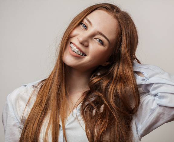 Young brunette woman with clear ceramic braces smiling