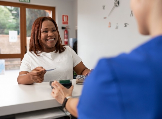 Orthodontic patient handing payment card to front desk team member