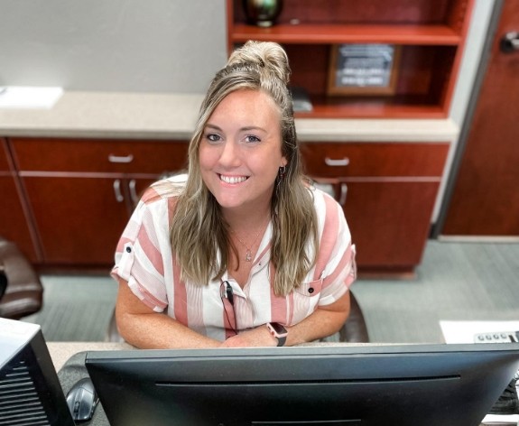 Smiling orthodontic team member sitting at front desk