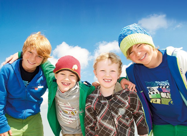 Four young boys grinning outdoors after interceptive orthodontics in Oklahoma City