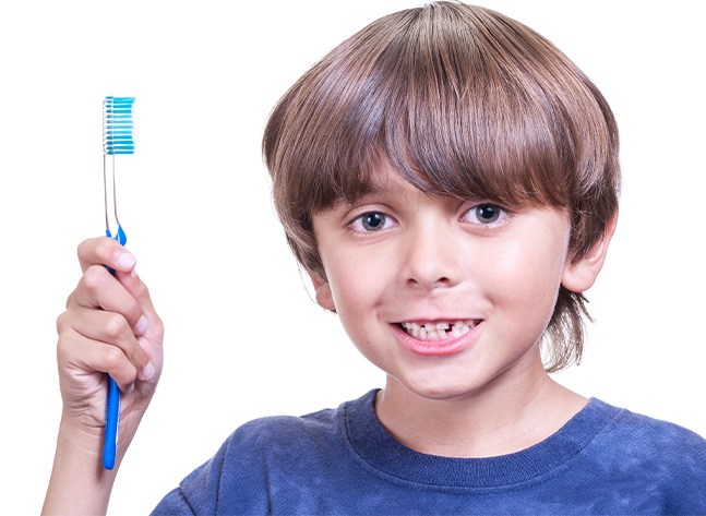Young boy with misaligned teeth holding a toothbrush