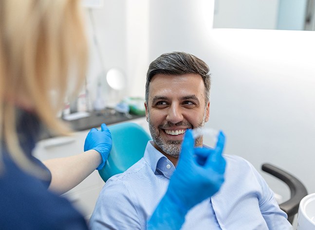 Smiling patient looking at dentist holding blue glove