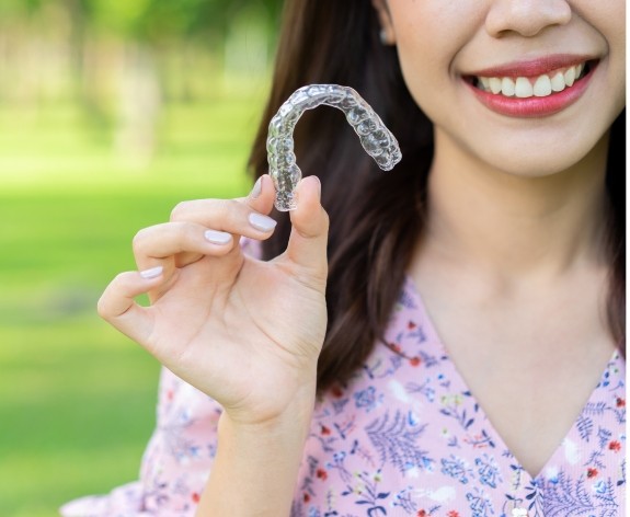 Woman holding Invisalign aligner outdoors
