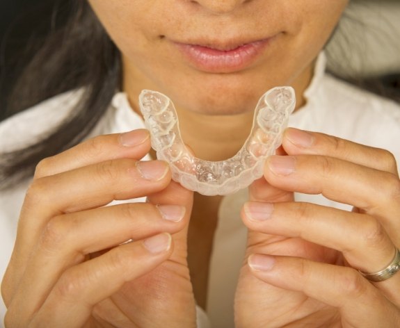 Close up of person about to put Invisalign tray in their mouth
