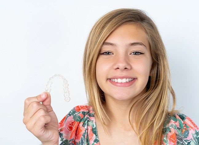 Teenage girl holding Invisalign clear aligner in Oklahoma City