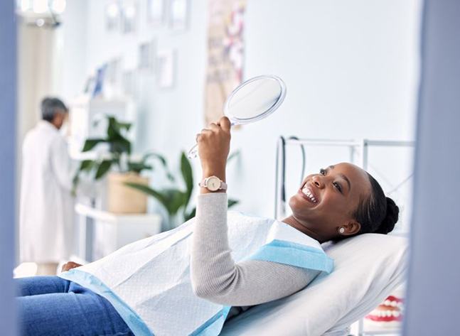 Dental patient looking at her smile in mirror