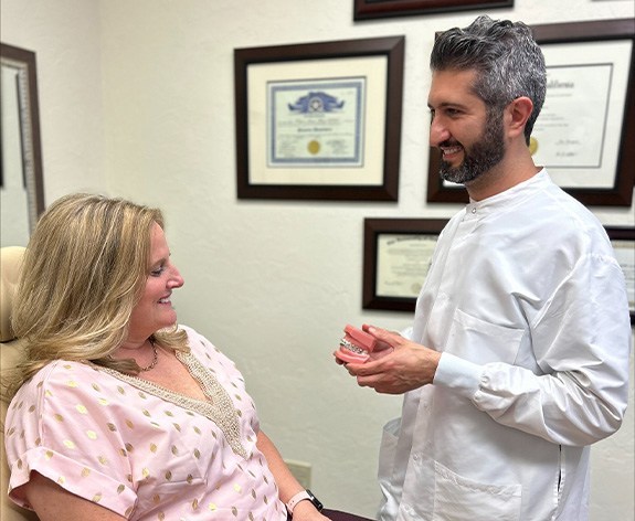 Doctor Ishani smiling while showing a patient a model of the teeth