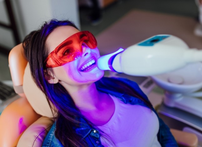 Woman getting professional teeth whitening in dental office