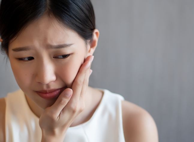 Woman holding the side of her jaw in pain