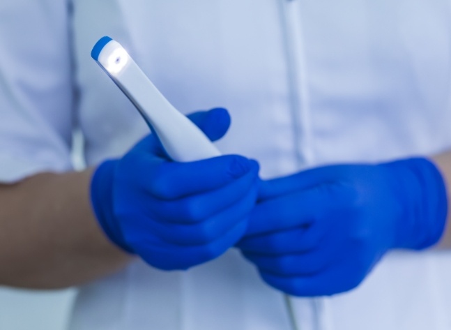 Two gloved hands holding an intraoral camera