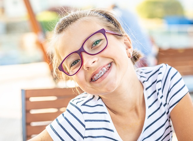 a child with purple glasses sitting outdoors