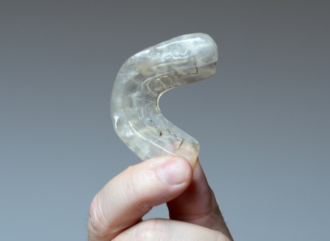 Hand holding a clear nightguard for bruxism