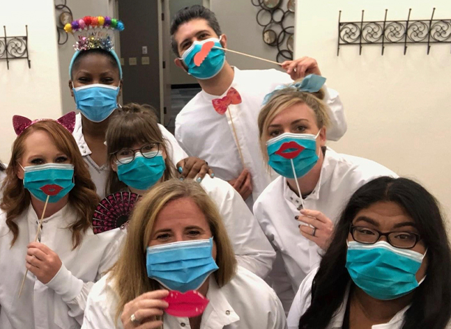 Casady Square Orthodontics team wearing face masks and holding sticks with fake mustaches and lips up to their faces