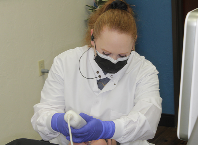 Team member scanning a patient's teeth with advanced orthodontic technology in Oklahoma City