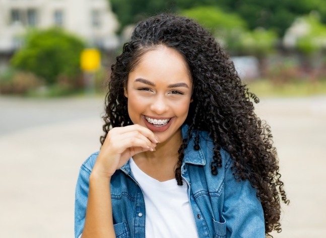 Young woman with denim jacket and braces smiling outdoors