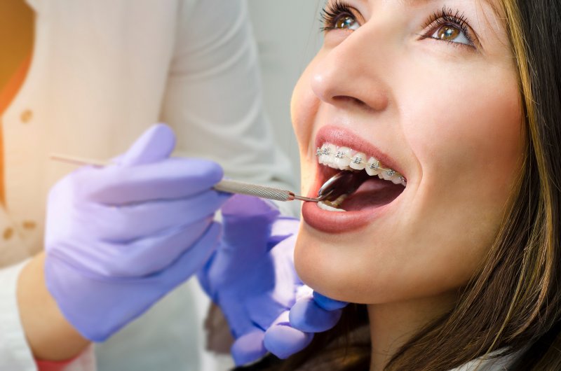 A woman with braces getting checked at her orthodontist appointment