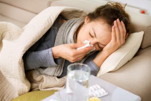 Sick woman on couch blowing her nose