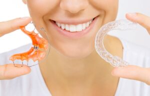 Nose to chin view of woman holding 2 different retainers