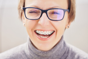 Close-up of young blonde woman with braces and glasses