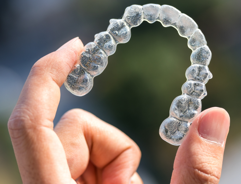 Hand holding invisalign retainer